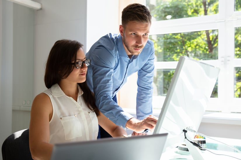 Businessman Standing Near Businesswoman Pointing At Computer Screen