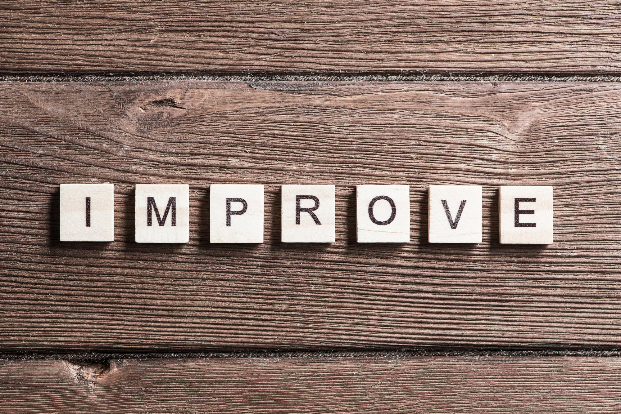 "Improve" spelled in wooden tiles, the right property management solutions help a business improve concept. 