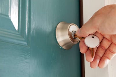 Image of a hand putting in a key in the keyhole of a door