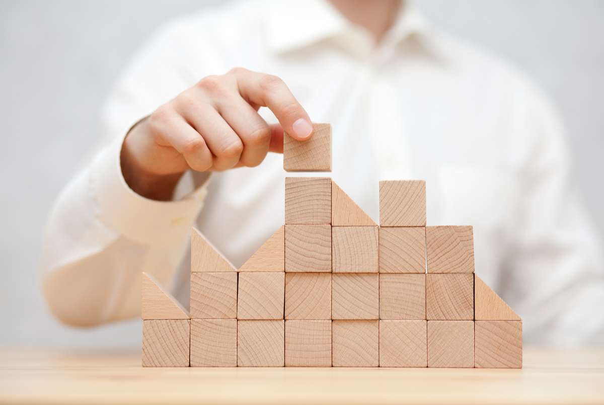 Mans hand stacking wooden blocks. Business development concept (R) (S)