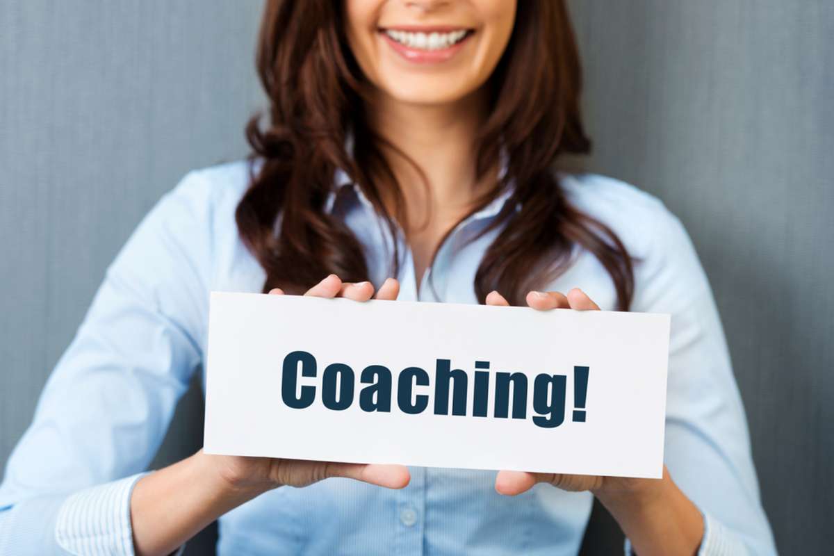 A woman holding a sign saying coaching, property management coach concept