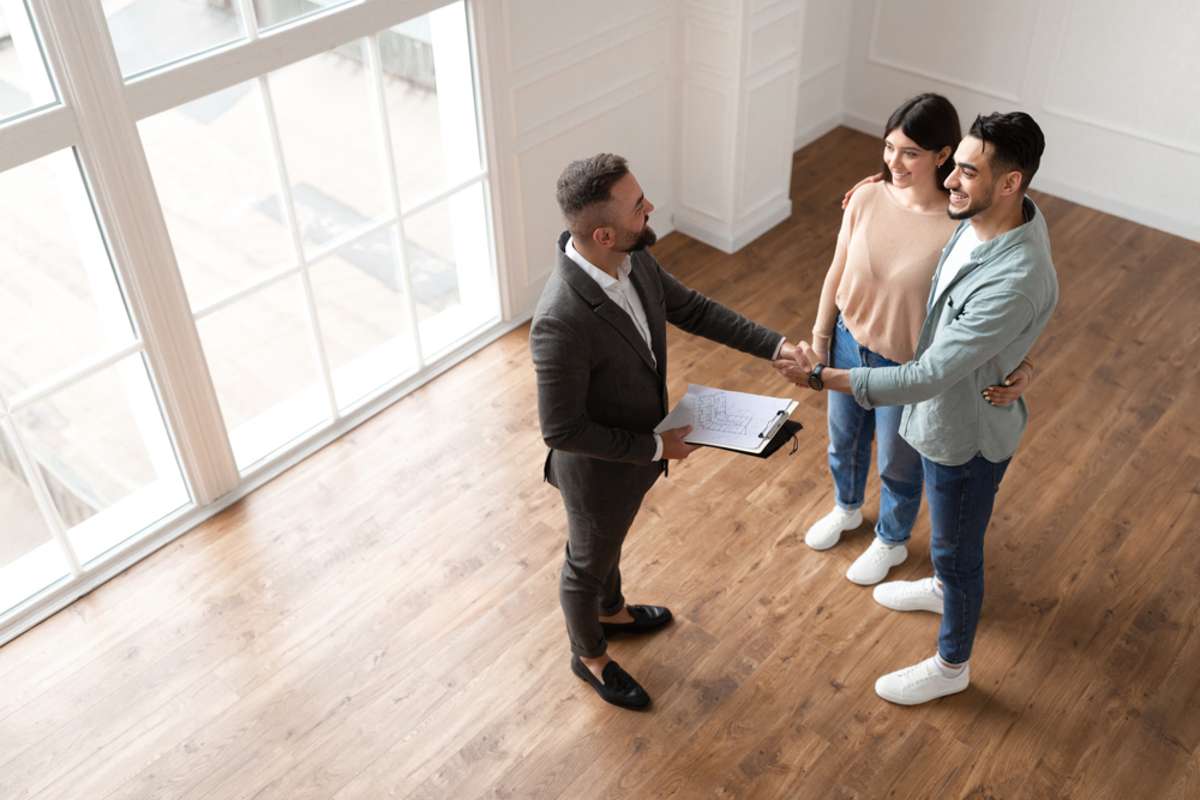 Above Top High Angle View Of Millennial Couple Buying New Apartment, Shaking Hands With Professional Real Estate Agent
