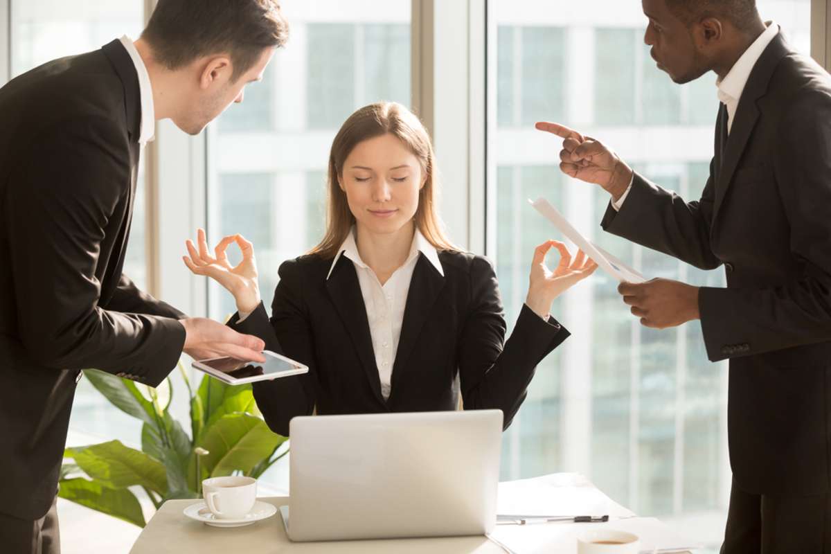 Beautiful businesswoman meditating at workplace, ignoring work, not listening to annoying clients or bothering colleagues talking to her