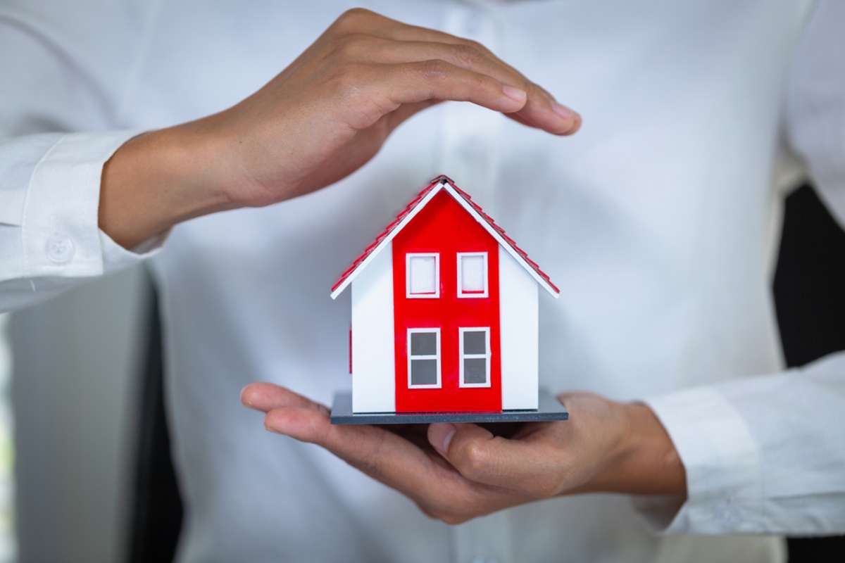 Businessmen use their hands to protect the red roofs, the concept of protecting houses using the gestures and symbols of real estate investors