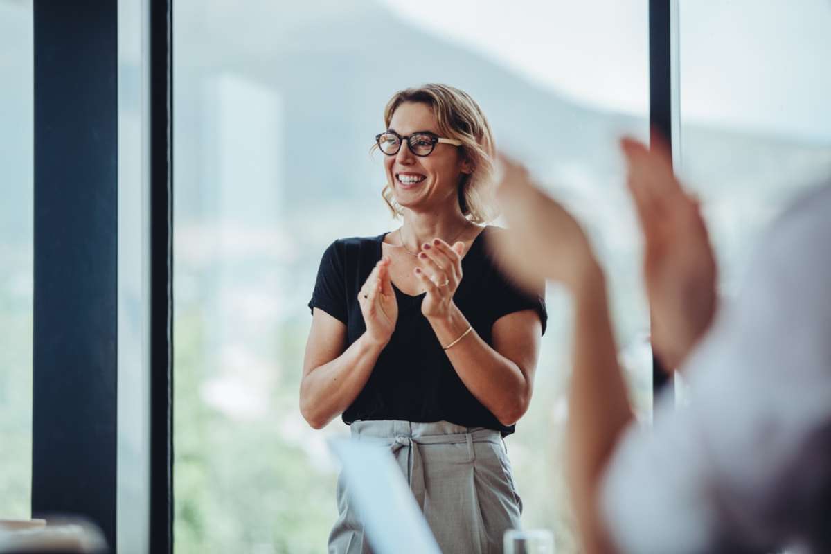 Businesswoman clapping hands after successful brainstorming session in boardroom