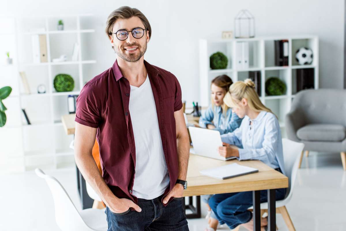 Handsome man standing in office of startup project and looking at camera