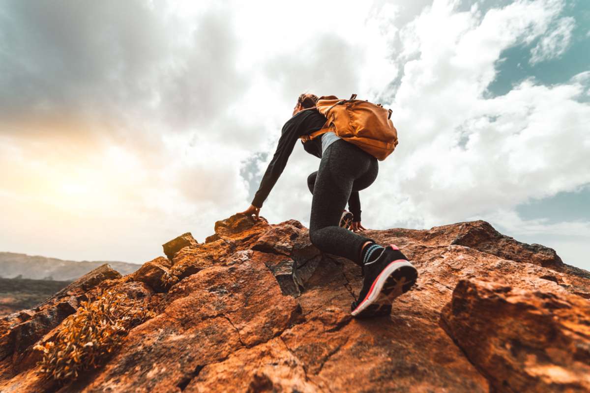 Woman hiker on sunrise mountain peak, property management success concept. 