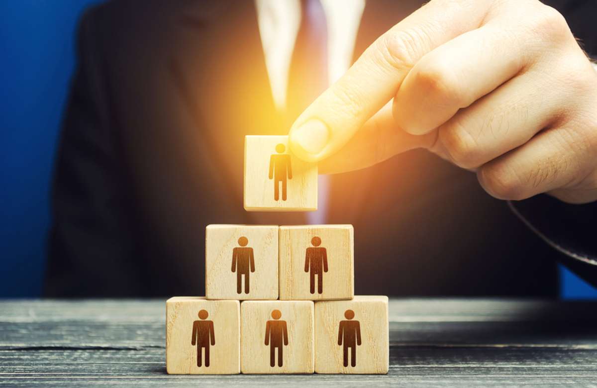 A hand stacking wooden blocks with people on them, property management valuation expert concept. 