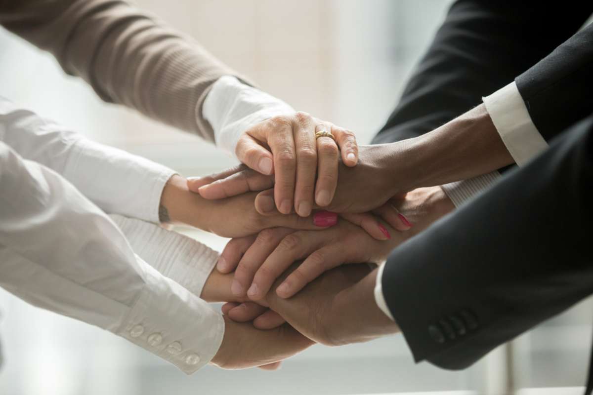 people putting stacked hands together promising help and support