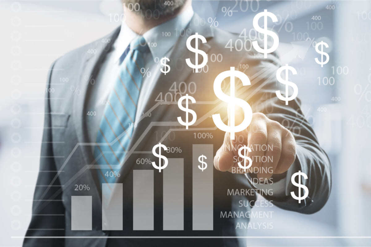 A man in a suit tapping on dollar signs