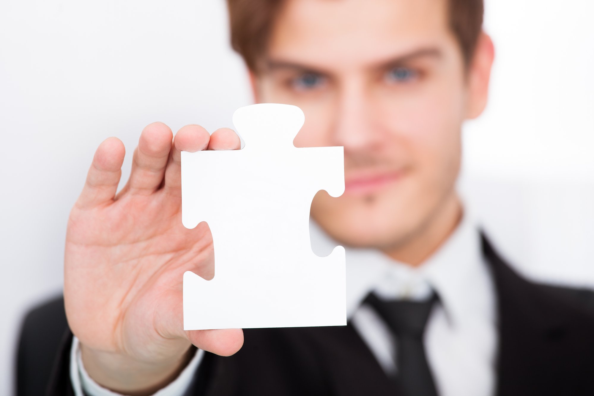 Man in a suit holding a puzzle piece 