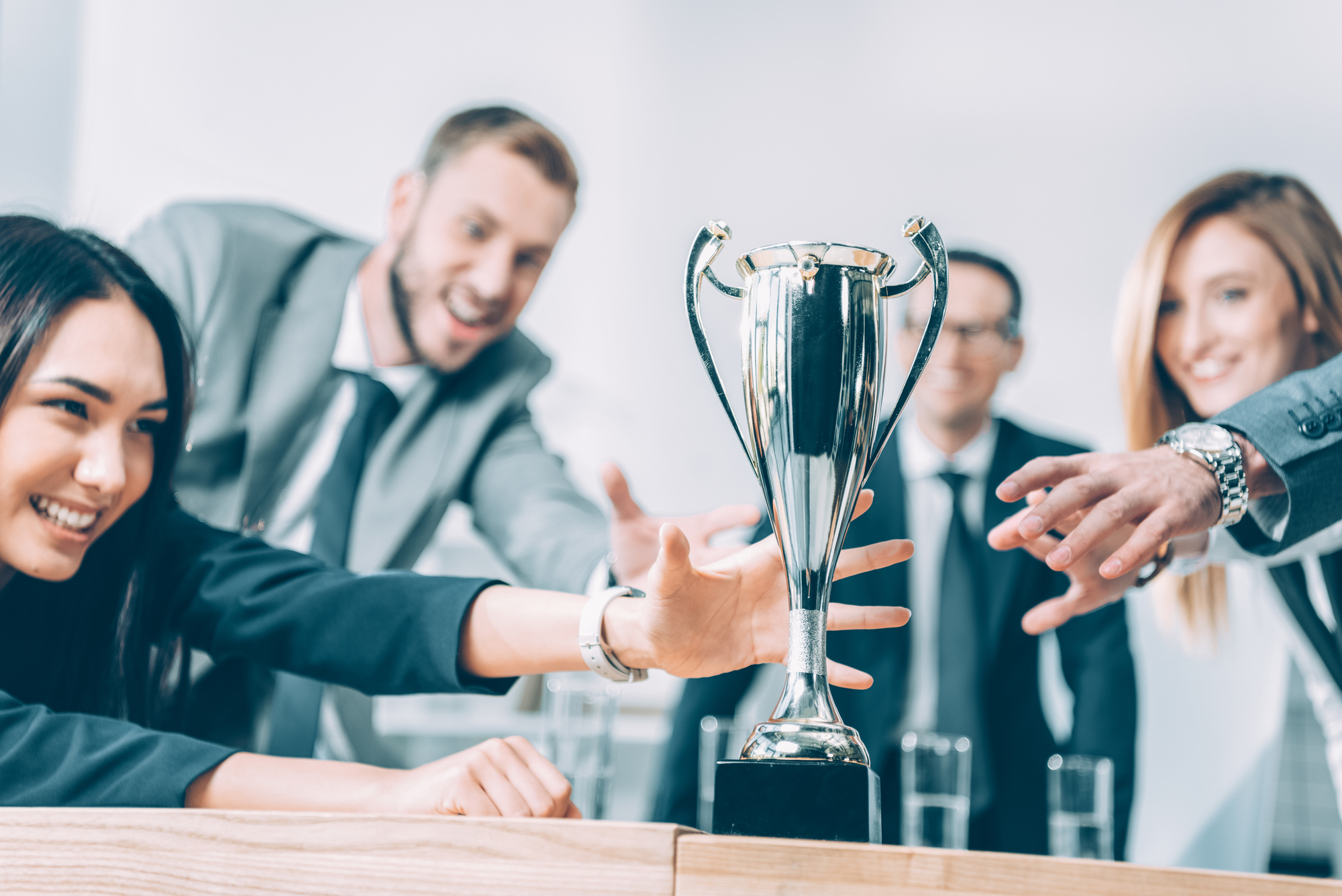 A group of businessmen racing to grab a trophy on a table