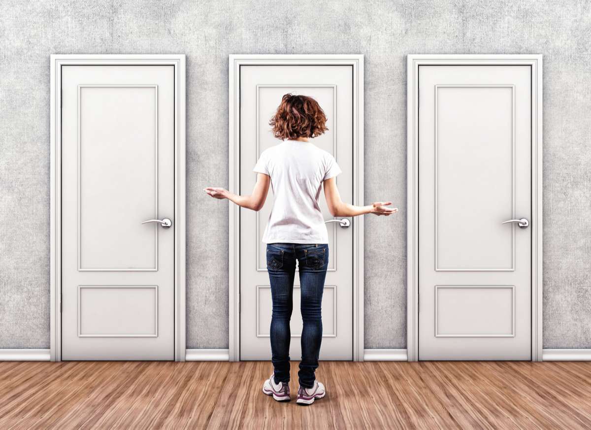Lady standing in front of 3 doors choosing which one to open