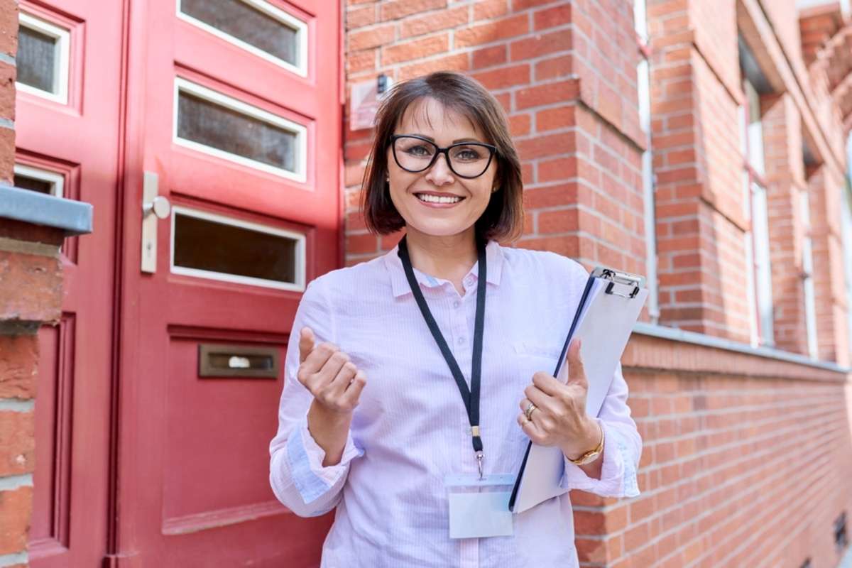 A smiling woman in front of a building, effective property management concept. 