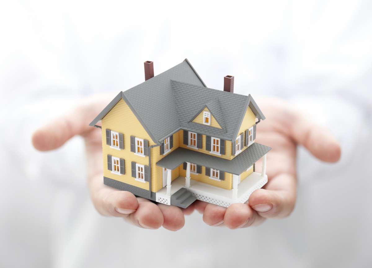 A pair of hands holding a house model
